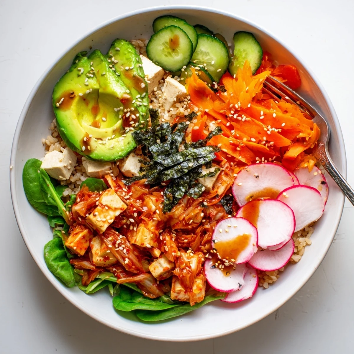 A colorful fermented vegetable bowl topped with kimchi, fresh greens, and avocado.  