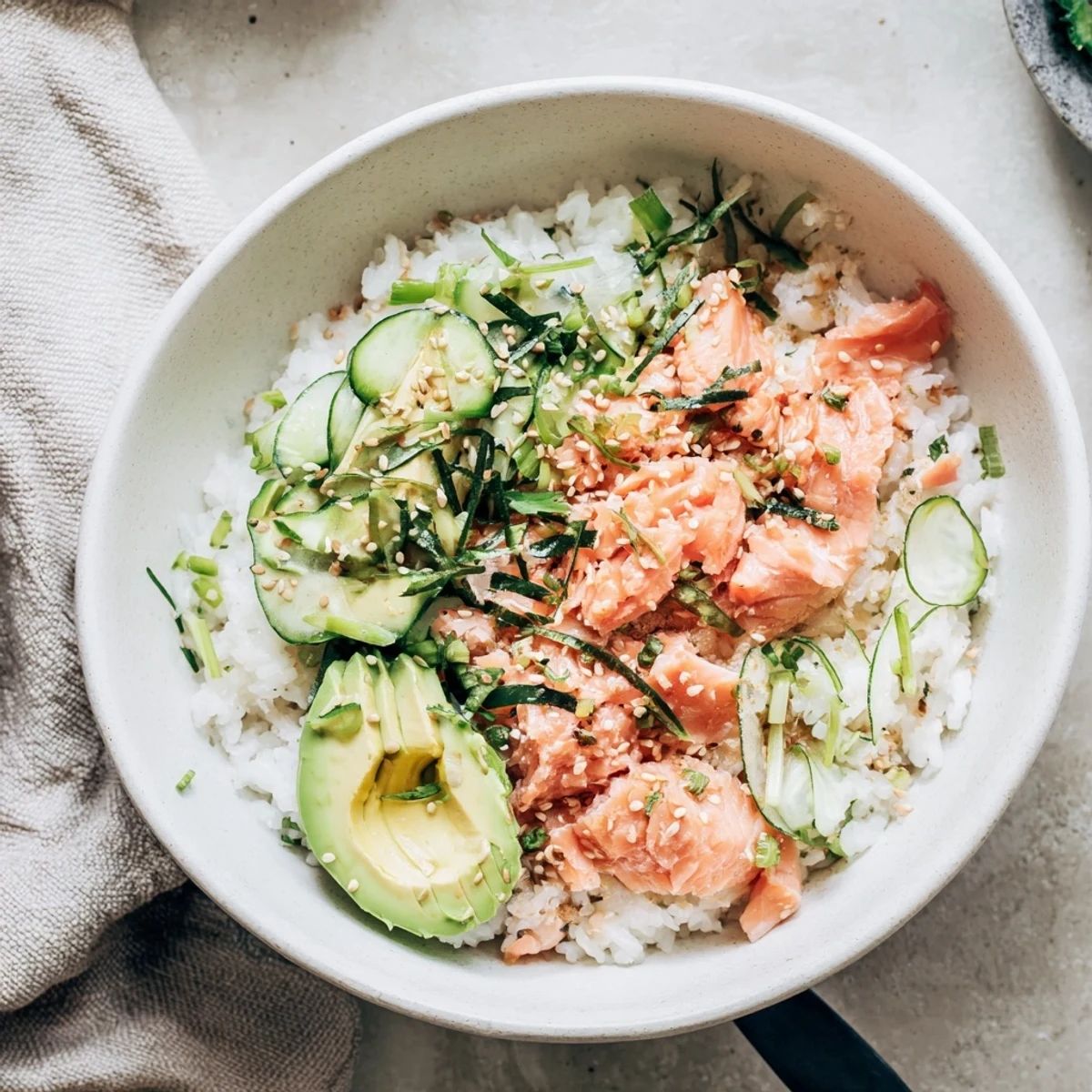 Leftover salmon and rice bowl topped with fresh avocado and cucumber slices.  