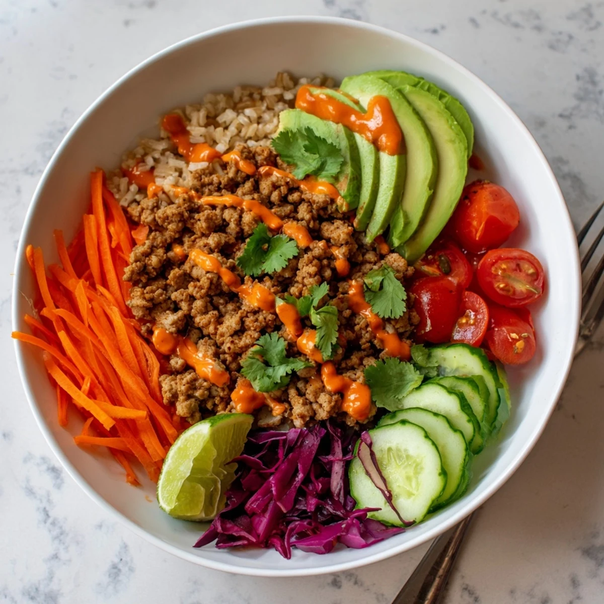 Colorful plant-based meat bowl topped with fresh veggies and zesty lime wedges.  