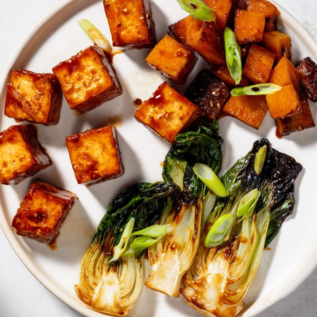 Golden-brown miso-glazed tofu and winter squash alongside tender bok choy, a delicious vegan dish.