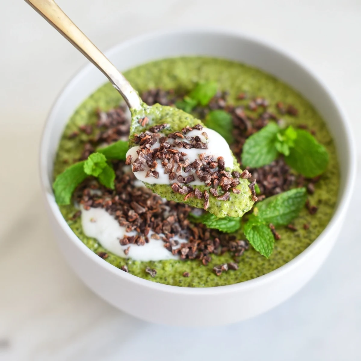A vibrant breakfast bowl of Grinch Green Mint Matcha Chia Pudding, boasting fresh mint and berries, visually appealing.