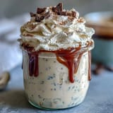 Creamy vanilla bean frappuccino overnight oats layered in a jar, topped with whipped cream and chocolate shavings for a dessert-like breakfast.