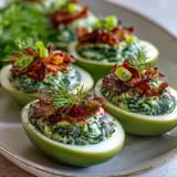 Bright green spinach deviled eggs topped with crispy ham bits for a playful, savory appetizer.