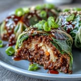 Fragrant Korean cabbage rolls featuring seasoned ground beef, gently steamed for juicy flavor and served with zesty sauce.  