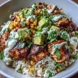 Hearty Street Corn Chicken Rice Bowls served with sliced avocado and a lime wedge.