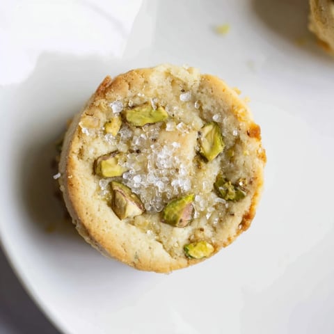 Golden, crisp Salted Pistachio Slice & Bake Shortbread cookies sprinkled with flaky sea salt, ready to enjoy.