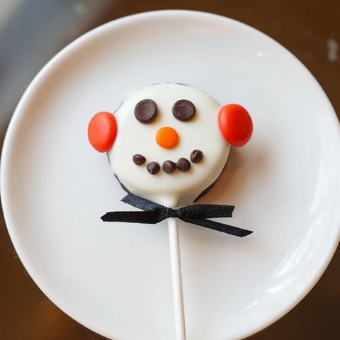Festive Oreo Snowman Pops, dipped in white chocolate, ready to bring smiles to your winter dessert table.