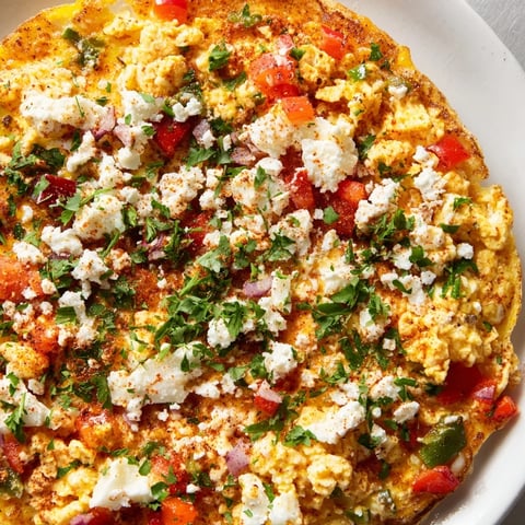A close-up shot of steaming Turkish Menemen Eggs pizza, glistening with fresh herbs and feta.