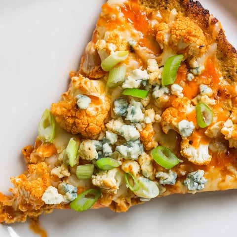 Freshly baked Buffalo Cauliflower Pizza with golden crust, melted mozzarella, and sliced green onions on a rustic wooden board.  