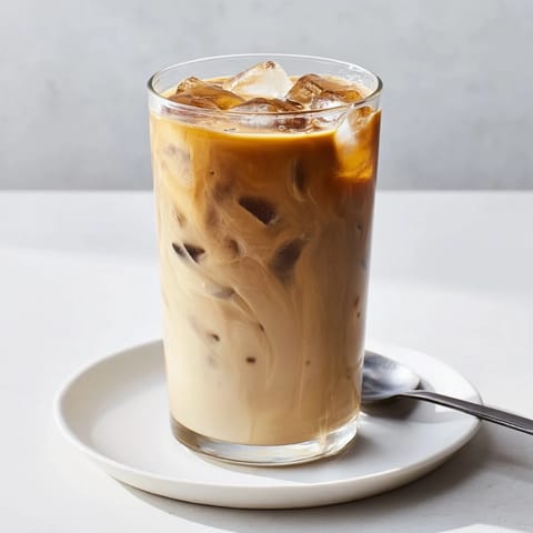 Rich tahini iced coffee pouring over ice, showcasing Middle Eastern flavor infusion.  