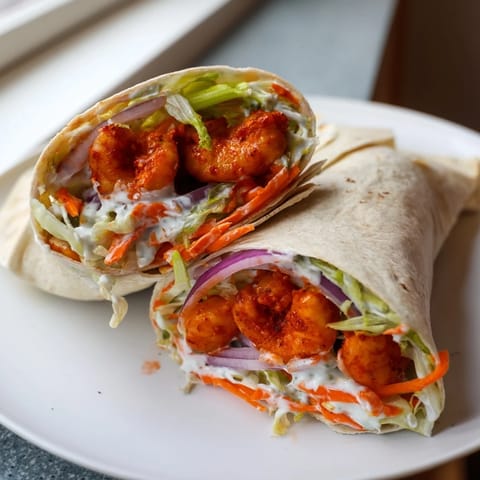 Spicy Buffalo Shrimp Wraps: a close-up of the flavorful, saucy shrimp nestled in a wrap.