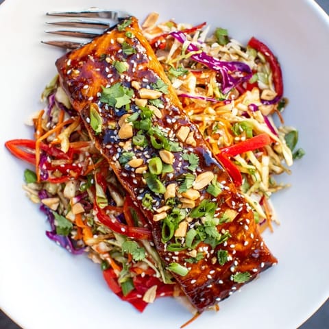 A beautifully plated Teriyaki Salmon & Asian Slaw Bowl with sesame seeds and fresh spring onions.