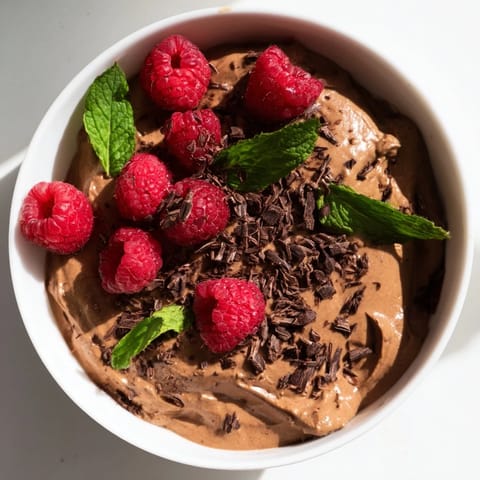 Dark chocolate shards and ruby raspberries accent this luscious avocado chocolate mousse dessert.