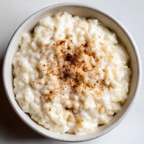 Enjoy a warm bowl of rice pudding made from leftover rice, sprinkled with cinnamon for serving.