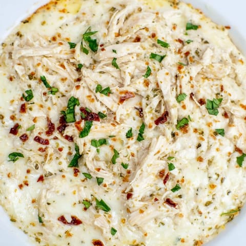 A close-up of lightened Marry Me Chicken Dip, showcasing sun-dried tomatoes and herbs; ready to be served.