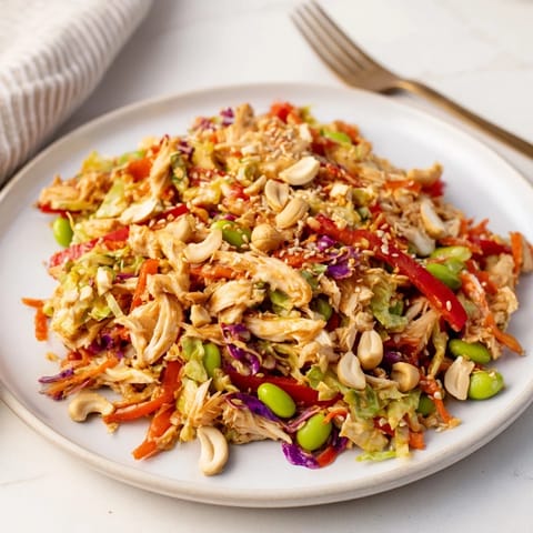 Vibrant Edamame Crunch Chicken Salad in a white bowl, topped with roasted cashews and toasted sesame seeds.