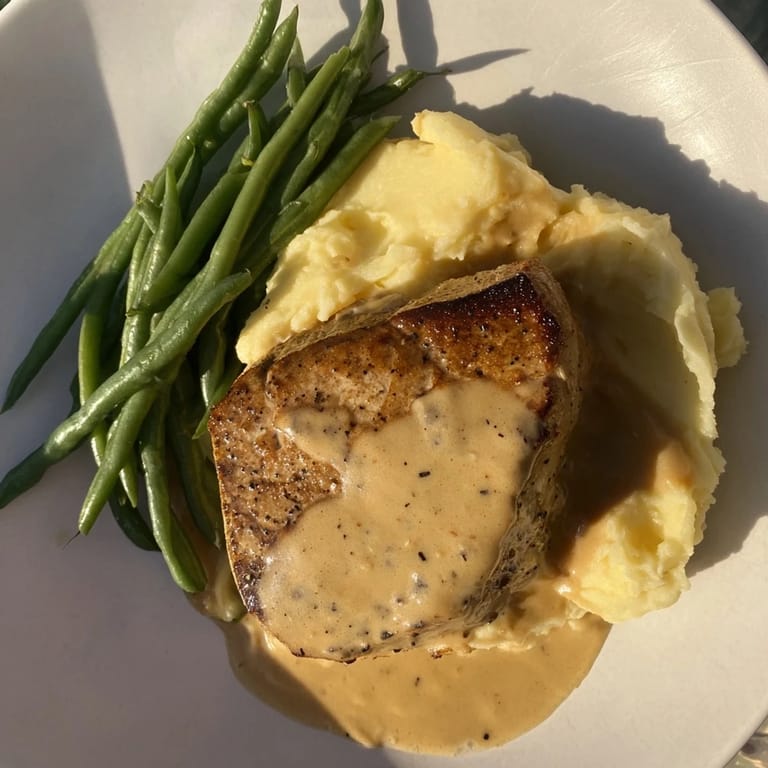 Tender Pork Chops & Cheddar Mash Bowl, glistening with savory gravy, served with bright green beans.