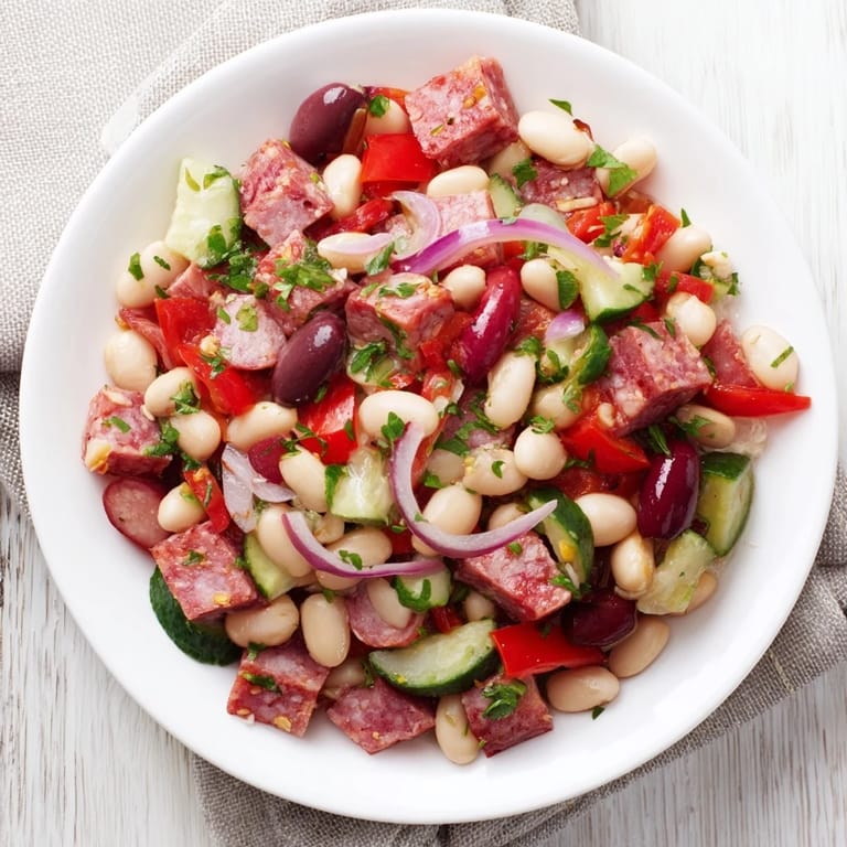 Savory salami and vibrant veggies elevate this Mediterranean Dense Bean Salad, perfectly ready to serve.