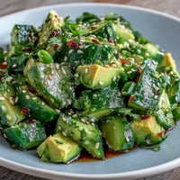 Vibrant smashed cucumber and avocado salad with sesame seeds, a refreshing side.